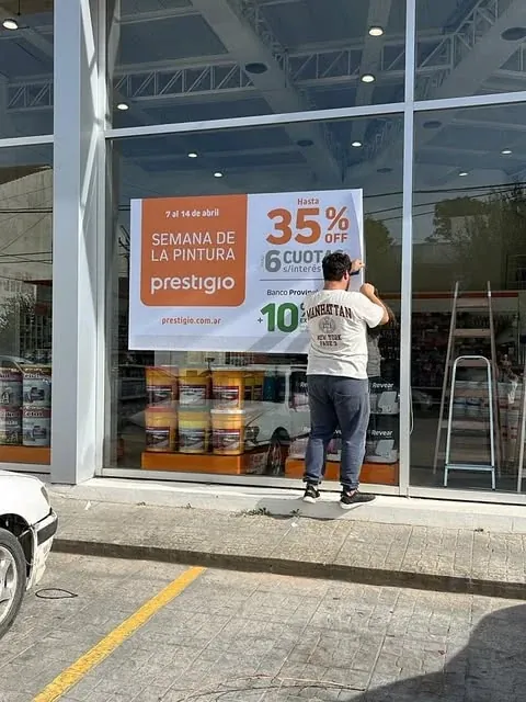 Colocación de una gráfica promocional en la vidriera de una pinturería